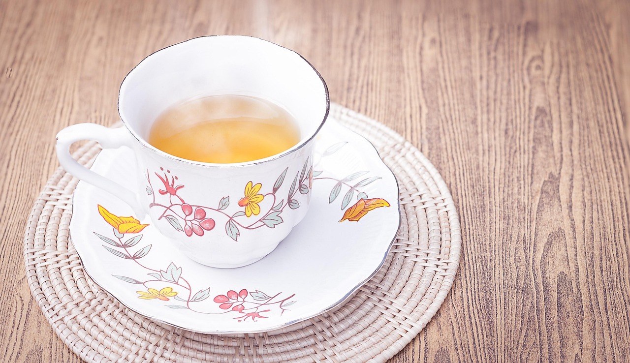 Tazza di tè fumante su un tavolo, con limone e foglie di tè, simbolo di benessere e perdita di peso.