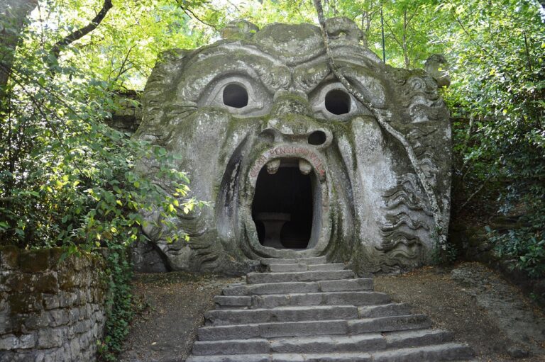 Bocca gigante nel Parco di Bomarzo, circondata da alberi nel bosco sacro, simbolo di arte e natura.