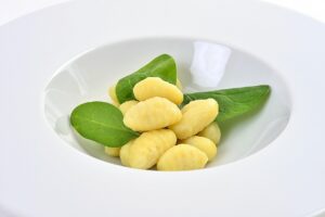 Gnocchi freschi dallo spiccato colore giallo, evidenziando un eccesso di farina nell'impasto.