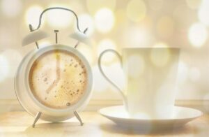 Caffè in tazza su un tavolo con un orologio che segna le 14:00, simbolo dell'argomento sull'effetto del caffè.